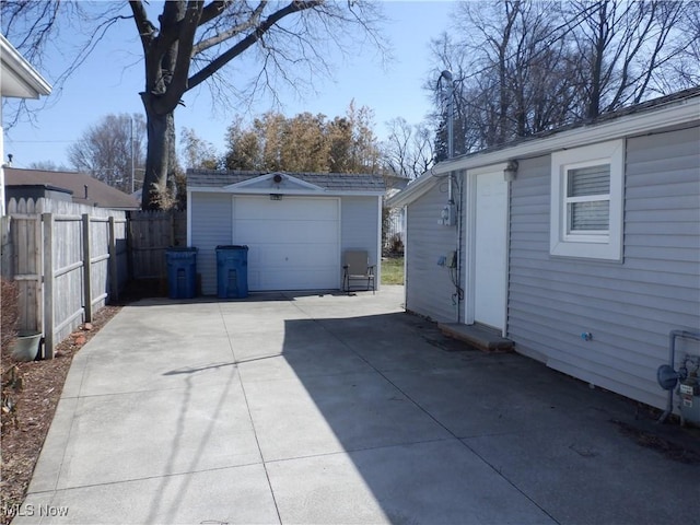 detached garage with concrete driveway and fence