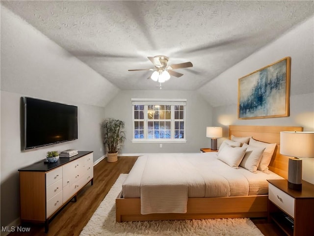 bedroom featuring lofted ceiling, dark wood-style floors, baseboards, and a textured ceiling