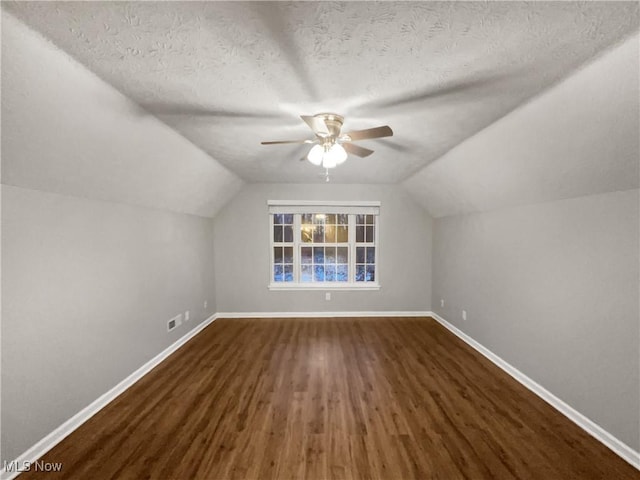 bonus room featuring visible vents, baseboards, a textured ceiling, and dark wood-type flooring