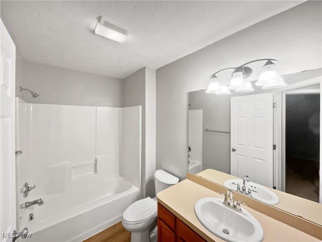 bathroom featuring vanity, wood finished floors, shower / washtub combination, a textured ceiling, and toilet