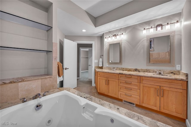 full bathroom with double vanity, a tub with jets, visible vents, and a sink