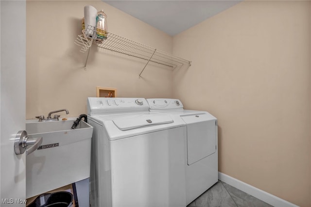 clothes washing area with laundry area, washer and dryer, baseboards, and a sink