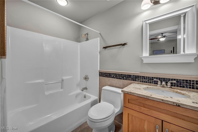 full bathroom featuring toilet, shower / tub combination, tile walls, wainscoting, and vanity