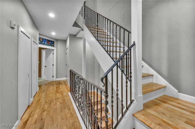 stairs with recessed lighting, wood finished floors, and baseboards