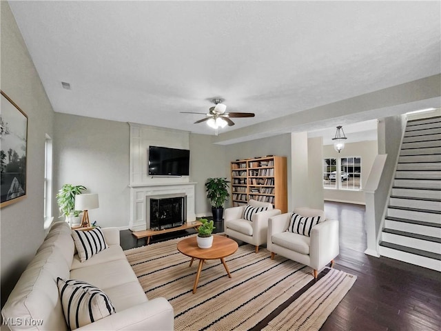 living room featuring visible vents, wood finished floors, a fireplace, ceiling fan, and stairs