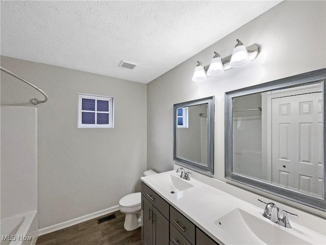 full bath with wood finished floors, visible vents, a sink, a textured ceiling, and toilet