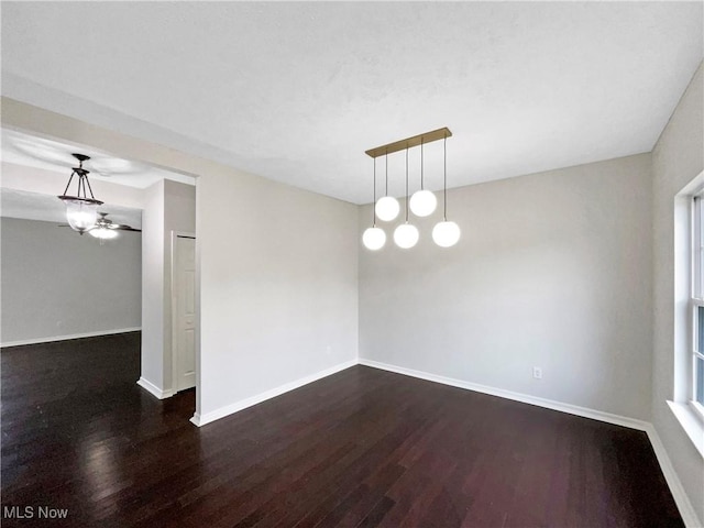 spare room featuring baseboards, plenty of natural light, and dark wood-style floors