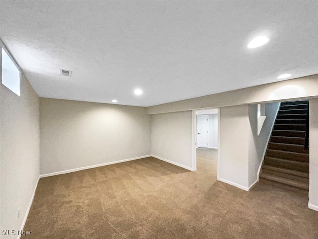 finished below grade area featuring visible vents, baseboards, stairway, carpet floors, and recessed lighting