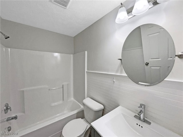 full bath featuring visible vents, wainscoting, bathtub / shower combination, a textured ceiling, and toilet