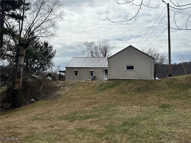 rear view of property featuring metal roof, a lawn, and central AC unit