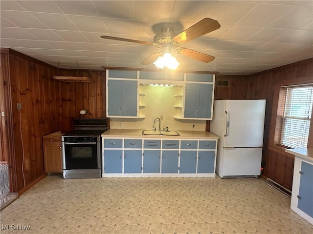 kitchen with wood walls, gas range oven, and freestanding refrigerator