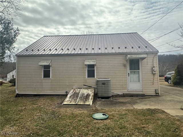 rear view of house with central AC unit and metal roof