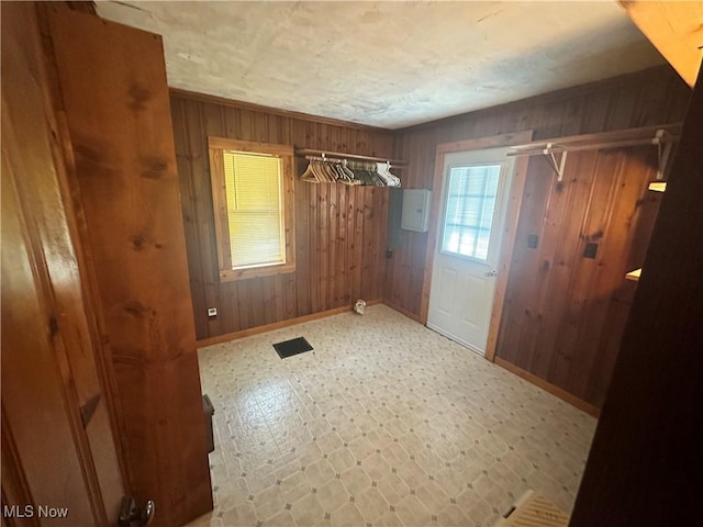 doorway featuring tile patterned floors, wooden walls, electric panel, and baseboards