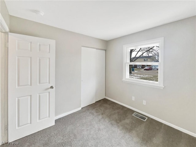 unfurnished bedroom featuring carpet flooring, baseboards, visible vents, and a closet