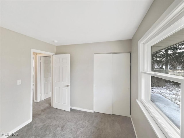 unfurnished bedroom featuring a closet, baseboards, and carpet floors