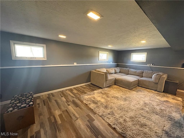 unfurnished living room with wood finished floors, baseboards, a wealth of natural light, and a textured ceiling