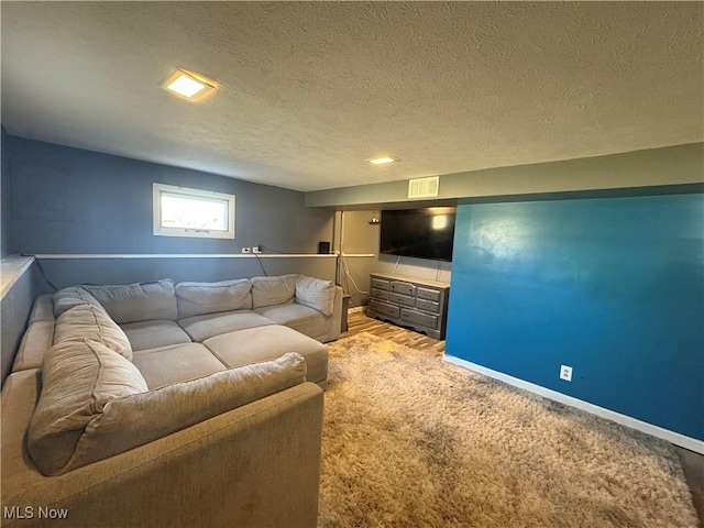 living area with visible vents, carpet floors, a textured ceiling, and baseboards