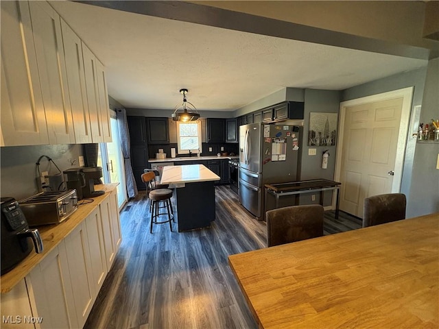 kitchen featuring a sink, a kitchen breakfast bar, dark wood finished floors, a center island, and light countertops