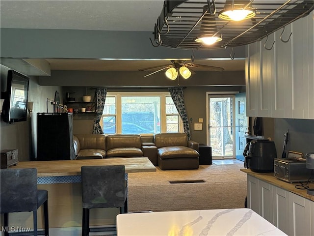 carpeted living area with a ceiling fan