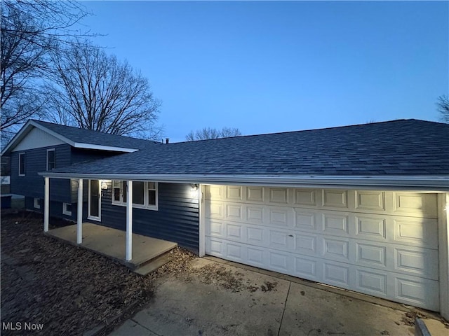 view of property exterior featuring a garage, roof with shingles, and driveway