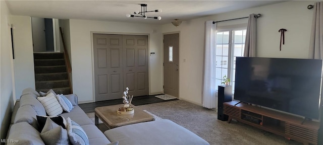 living area with an inviting chandelier, stairway, and carpet flooring