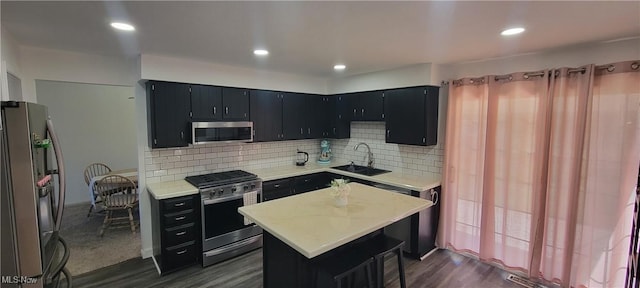 kitchen with a sink, backsplash, appliances with stainless steel finishes, light countertops, and dark cabinets