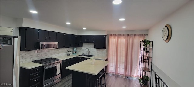 kitchen with a sink, appliances with stainless steel finishes, dark cabinetry, and light countertops