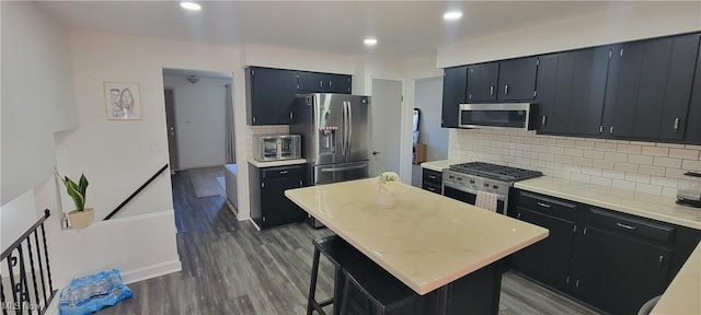 kitchen featuring recessed lighting, dark wood-style flooring, light countertops, appliances with stainless steel finishes, and tasteful backsplash