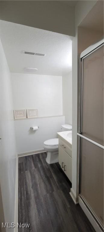 bathroom with a stall shower, toilet, wood finished floors, and vanity