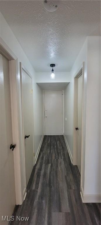 hall with baseboards, a textured ceiling, and dark wood finished floors