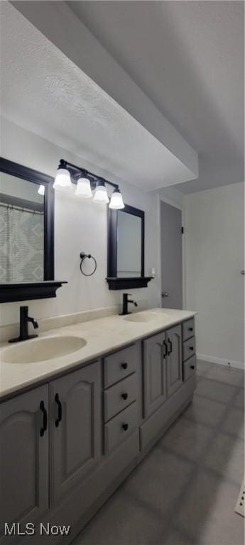 bathroom featuring double vanity, baseboards, and a sink