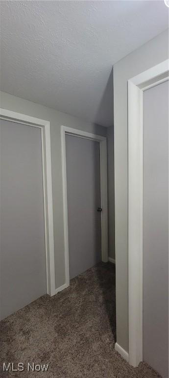 hallway with a textured ceiling and carpet flooring