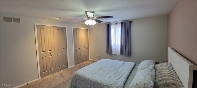 carpeted bedroom with ceiling fan, baseboards, visible vents, and multiple closets