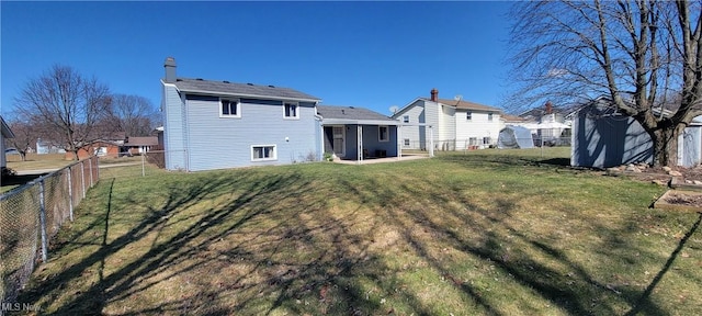 rear view of house with an outbuilding, a yard, a fenced backyard, and a chimney