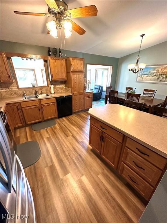 kitchen with brown cabinetry, plenty of natural light, light wood-style flooring, and black dishwasher