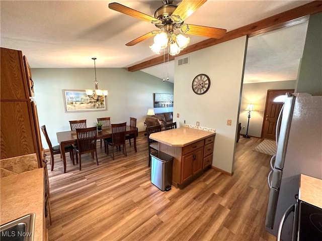 kitchen with visible vents, lofted ceiling with beams, freestanding refrigerator, light wood finished floors, and light countertops