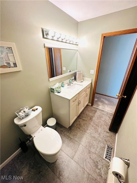 bathroom with vanity, toilet, baseboards, and visible vents