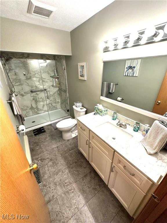 full bath with a marble finish shower, visible vents, toilet, and vanity