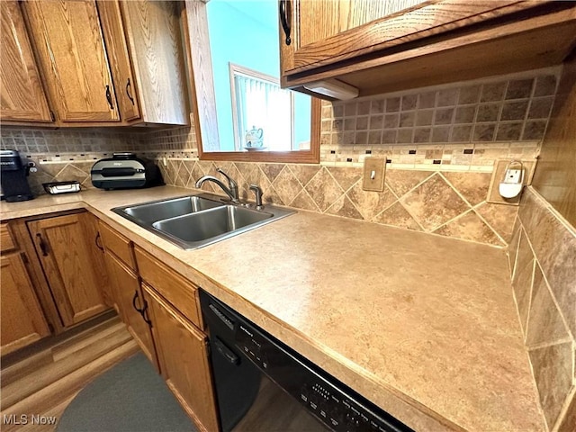 kitchen with brown cabinetry, a sink, decorative backsplash, light countertops, and dishwasher