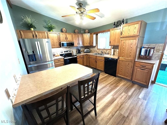 kitchen featuring ceiling fan, light wood-type flooring, decorative backsplash, stainless steel appliances, and a sink