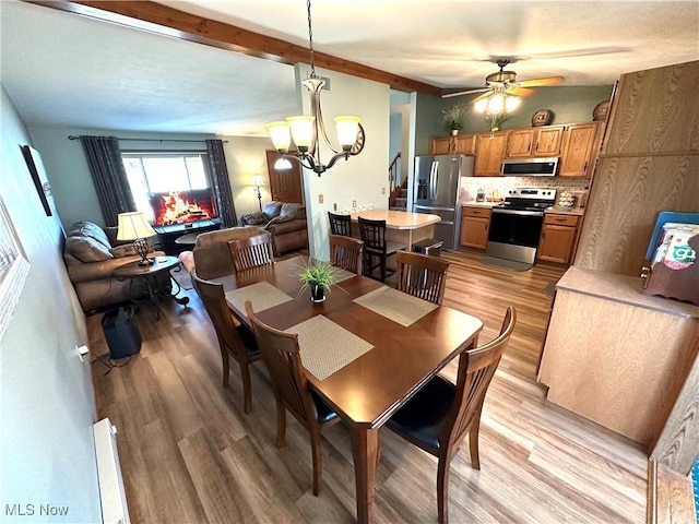 dining area with lofted ceiling with beams, light wood-style flooring, and ceiling fan with notable chandelier