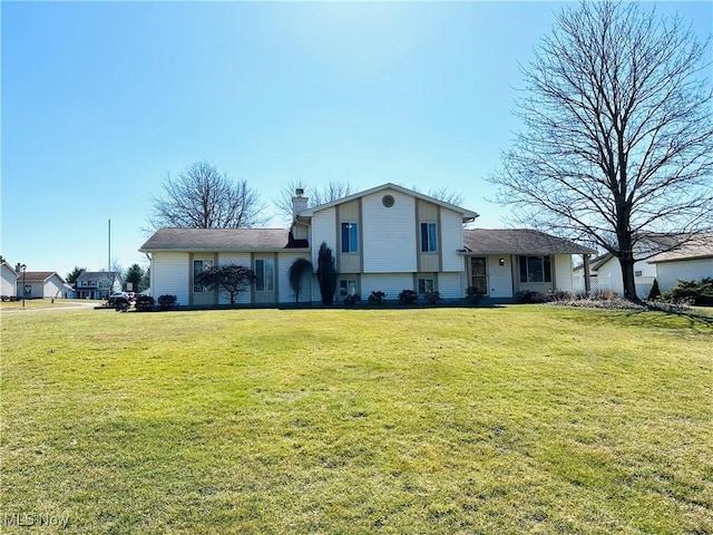 tri-level home featuring a front lawn and a chimney