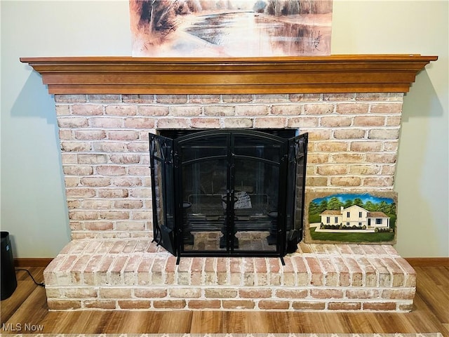 room details featuring a fireplace, baseboards, and wood finished floors