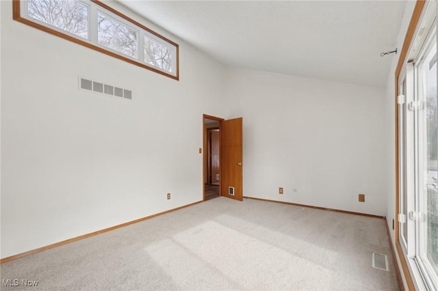 unfurnished room featuring visible vents, carpet flooring, high vaulted ceiling, and baseboards