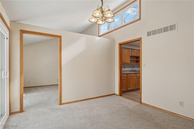 empty room featuring a sink, visible vents, light colored carpet, and a chandelier