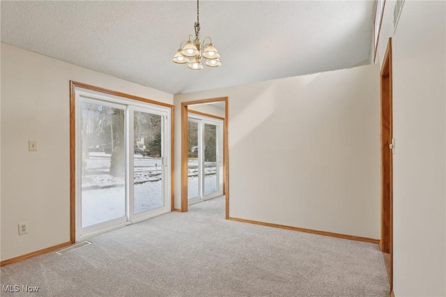 empty room with visible vents, baseboards, light colored carpet, vaulted ceiling, and an inviting chandelier