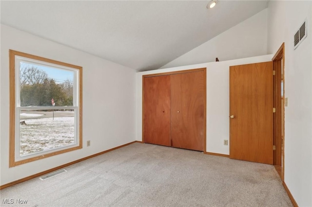 unfurnished bedroom with visible vents, baseboards, carpet, and vaulted ceiling