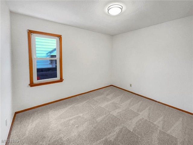 carpeted empty room with baseboards and a textured ceiling