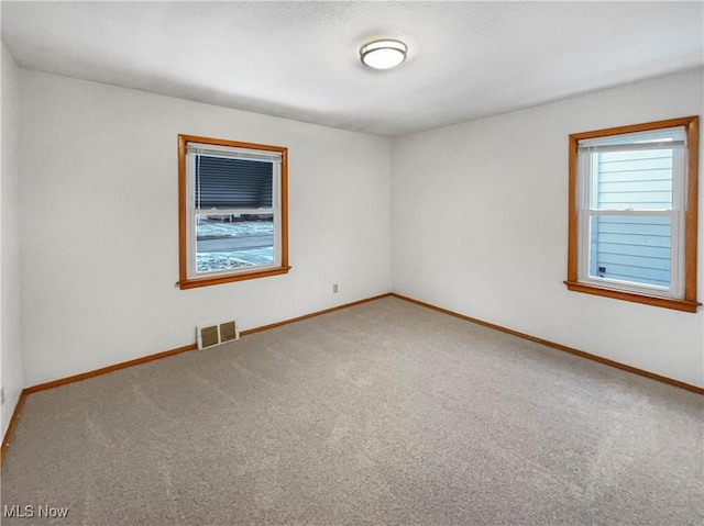 carpeted empty room with visible vents and baseboards