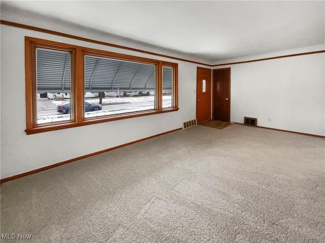 empty room with baseboards, visible vents, and carpet floors